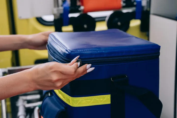 Close-up of hands handling an emergency medical kit in an ambulance setting.